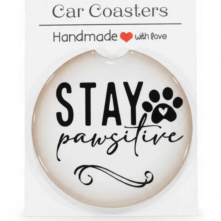 Car coaster with 'Stay Pawsitive' text on a wooden surface