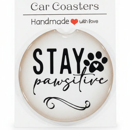 Car coaster with 'Stay Pawsitive' text on a wooden surface