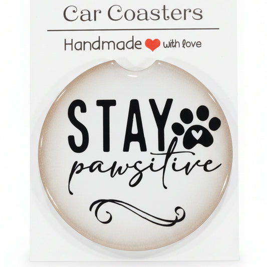 Car coaster with 'Stay Pawsitive' text on a wooden surface