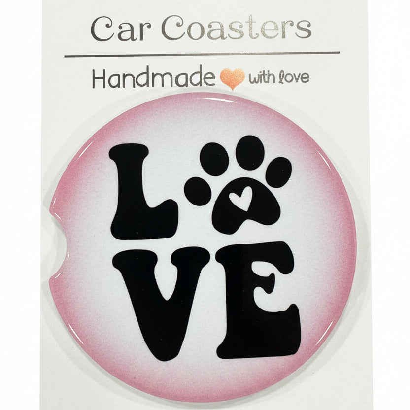 Round pink sticker with black paw print design and 'LOVE' text on a white card, placed on a wooden surface.