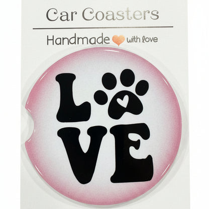 Round pink sticker with black paw print design and 'LOVE' text on a white card, placed on a wooden surface.