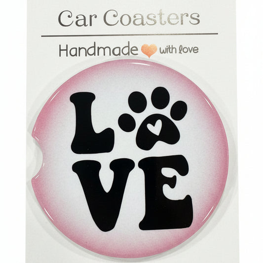 Round pink sticker with black paw print design and 'LOVE' text on a white card, placed on a wooden surface.
