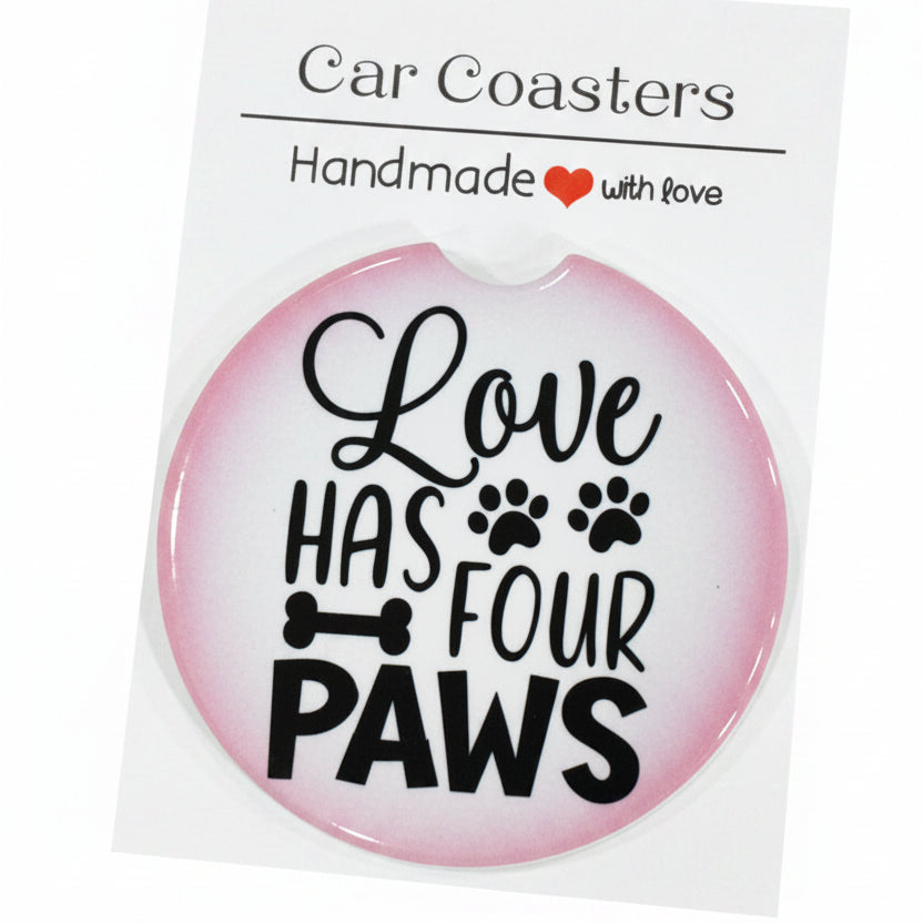 Car coaster with 'Love has four paws' text on a white card, placed on a wooden surface.
