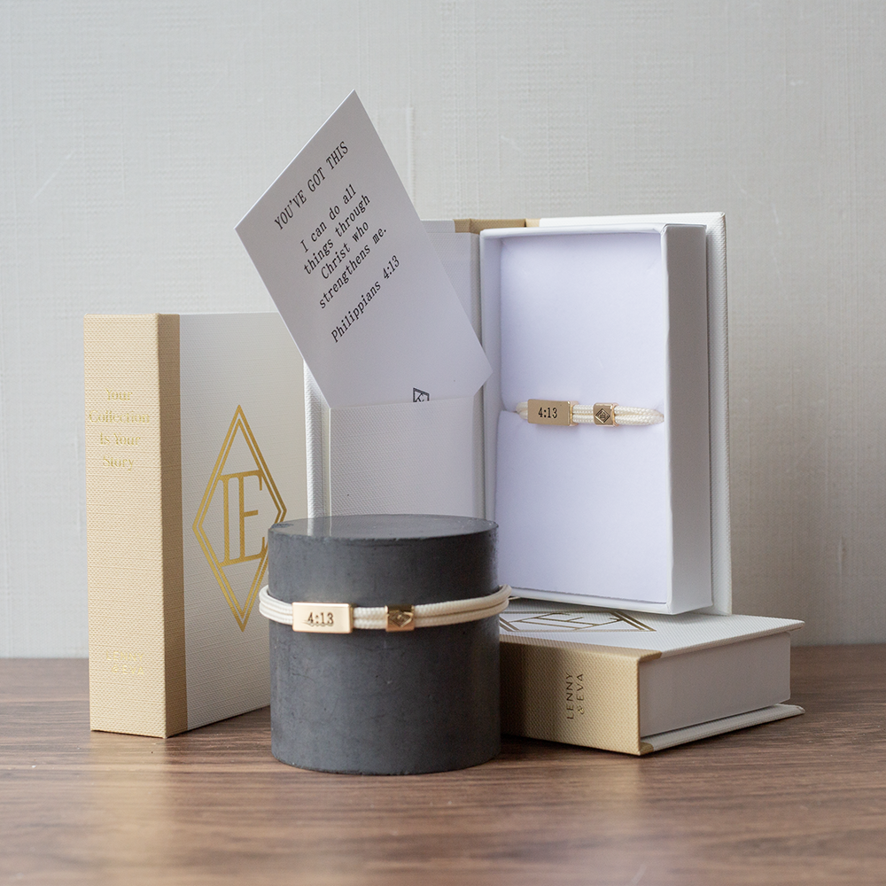 Gold bracelet in a black box with a white card on a wooden surface
