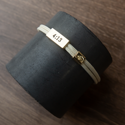 Bracelet with a gold tag displaying '4.13' on a dark cylindrical object.